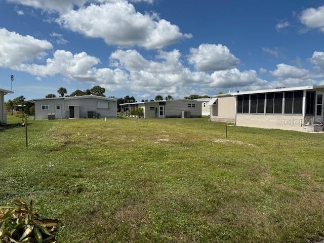 A vacant grassy lot sits between several manufactured homes under a bright, cloudy sky — 224 LA ROSAS, NORTH PORT, FL