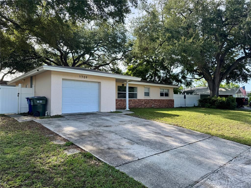 A single-story house with a white garage, brick accents, and a concrete driveway — 1709 EATON DRIVE NE, CLEARWATER, FL