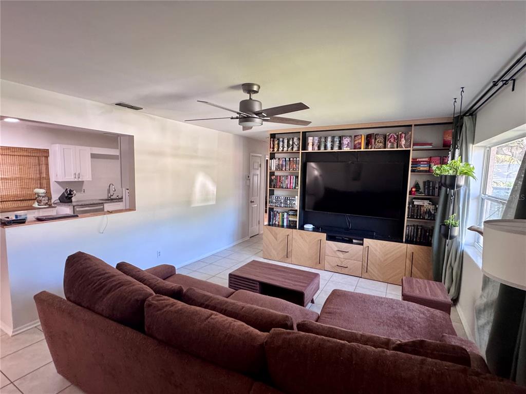 A living room features a large brown sectional, a built-in media center, and tile flooring — 1709 EATON DRIVE NE, CLEARWATER, FL