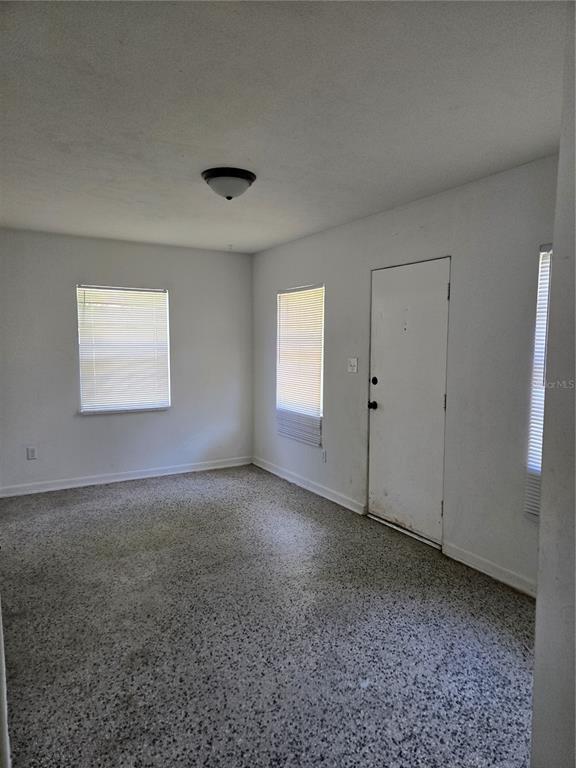 An empty room with white walls, three windows with blinds, and speckled flooring — 2109 S MILLS AVENUE, ORLANDO, FL