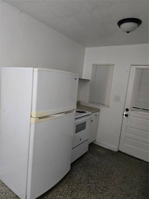 A kitchen features a white refrigerator, a white stove, and a door with blinds — 2109 S MILLS AVENUE, ORLANDO, FL