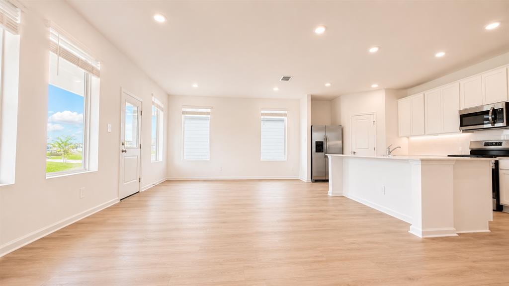 A modern kitchen features white cabinets, stainless steel appliances, and a central island with seating — 2998 GOOD VIBES WAY, CLERMONT, FL