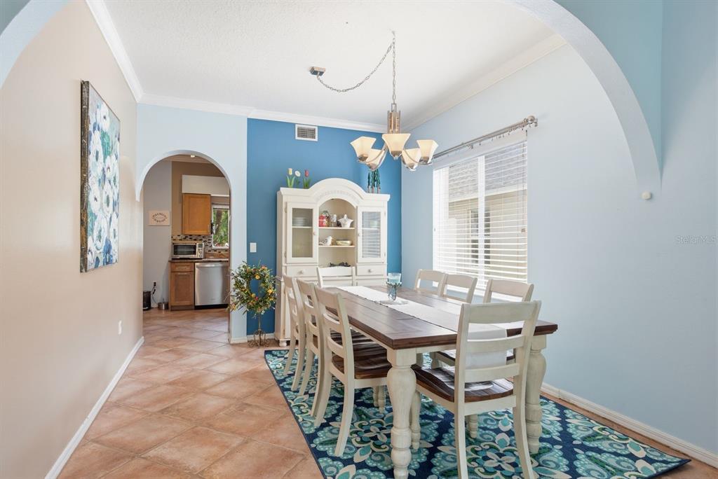 A dining room features a wooden table, white chairs, a hutch, and blue accent walls — 384 WINGATE CIRCLE, OLDSMAR, FL