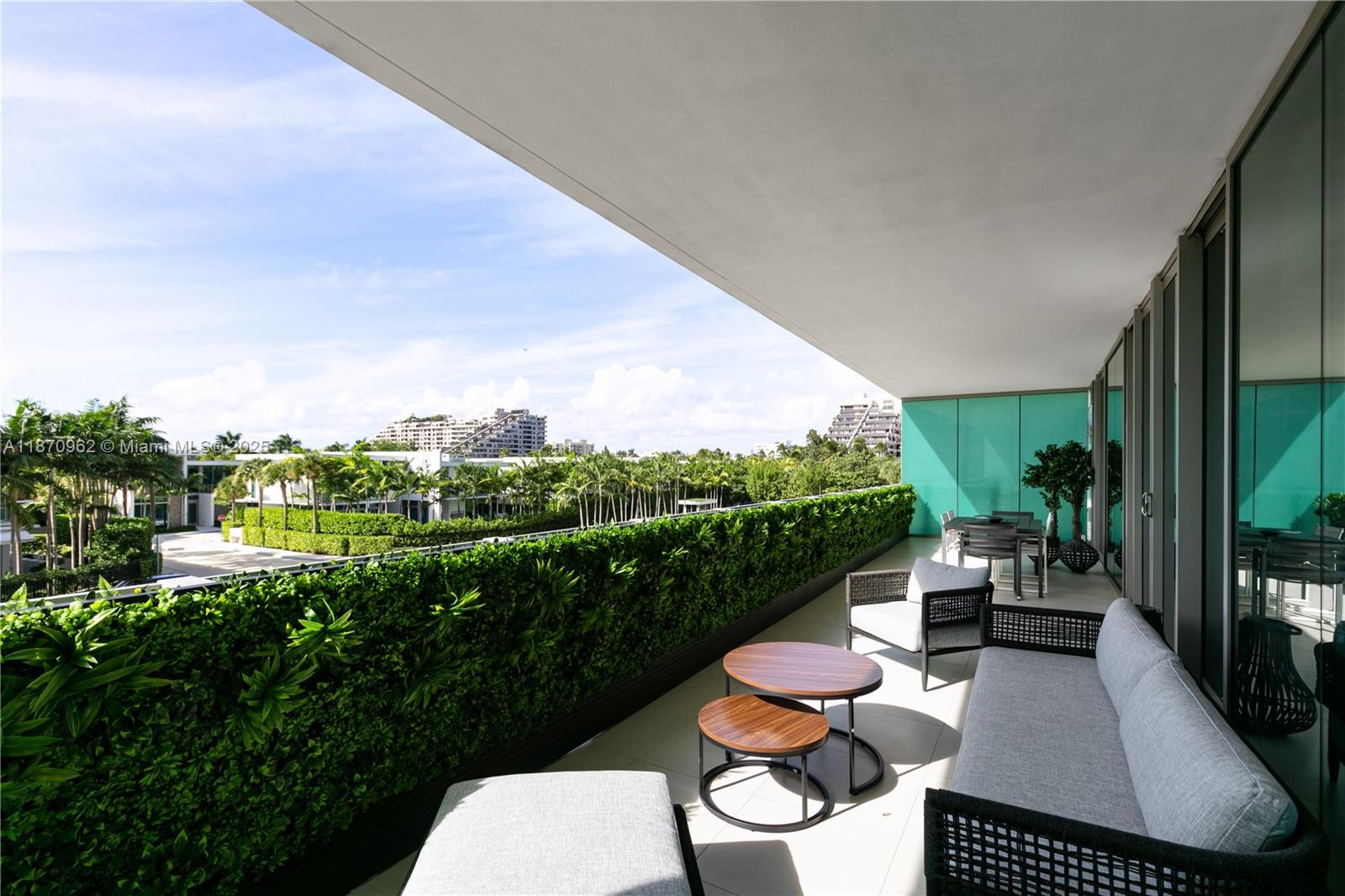 A balcony features a sofa, chairs, coffee tables, and a green privacy hedge overlooking trees — 360 Ocean Dr # 305S, Key Biscayne FL 33149, KEY BISCAYNE, FL