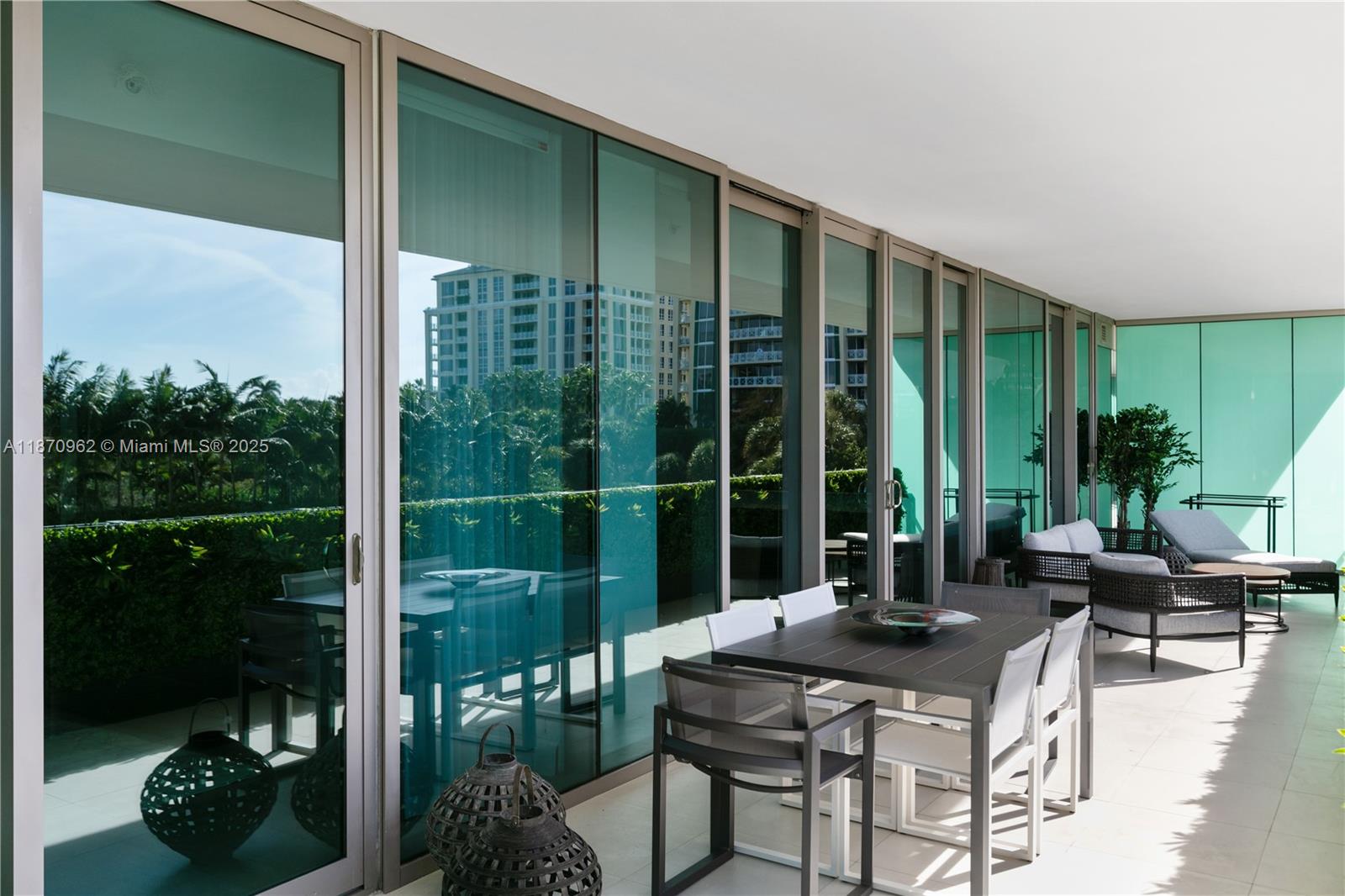 A modern balcony features glass sliding doors, outdoor dining furniture, and lounge chairs — 360 Ocean Dr # 305S, Key Biscayne FL 33149, KEY BISCAYNE, FL
