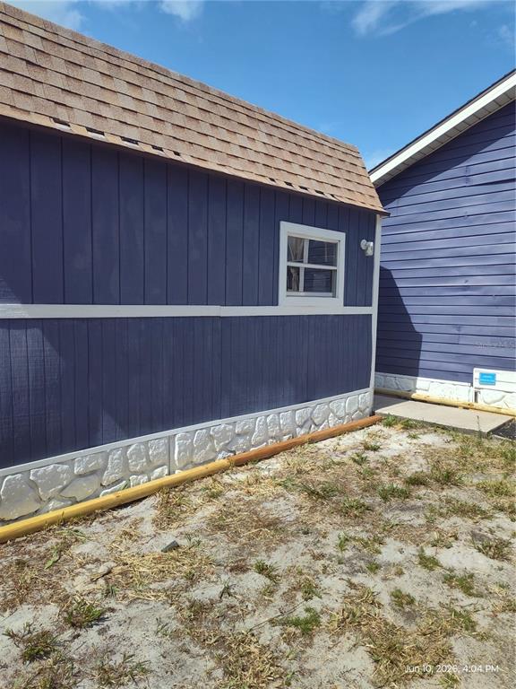 The exterior of a blue shed with a stone foundation sits next to a house — 140 BAY ROAD, OCKLAWAHA, FL