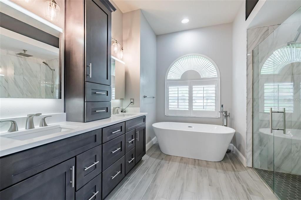 A bathroom features a double vanity with dark cabinets, white countertops, and two illuminated mirrors — 10131 PADDOCK OAKS DRIVE, RIVERVIEW, FL