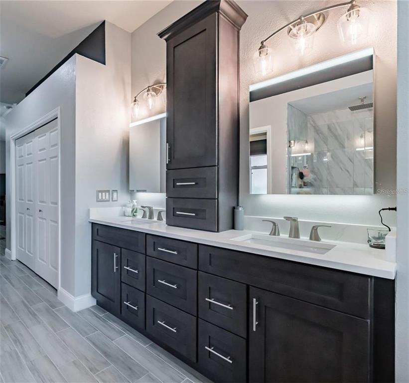 A modern bathroom features a dark wood vanity, a freestanding tub, and a glass shower — 10131 PADDOCK OAKS DRIVE, RIVERVIEW, FL