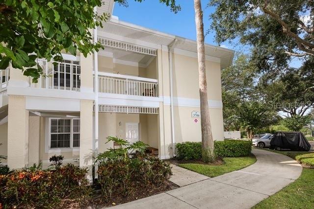 A two-story beige apartment building with balconies and a paved walkway in front — 3706 54TH DRIVE W UNIT 201, BRADENTON, FL