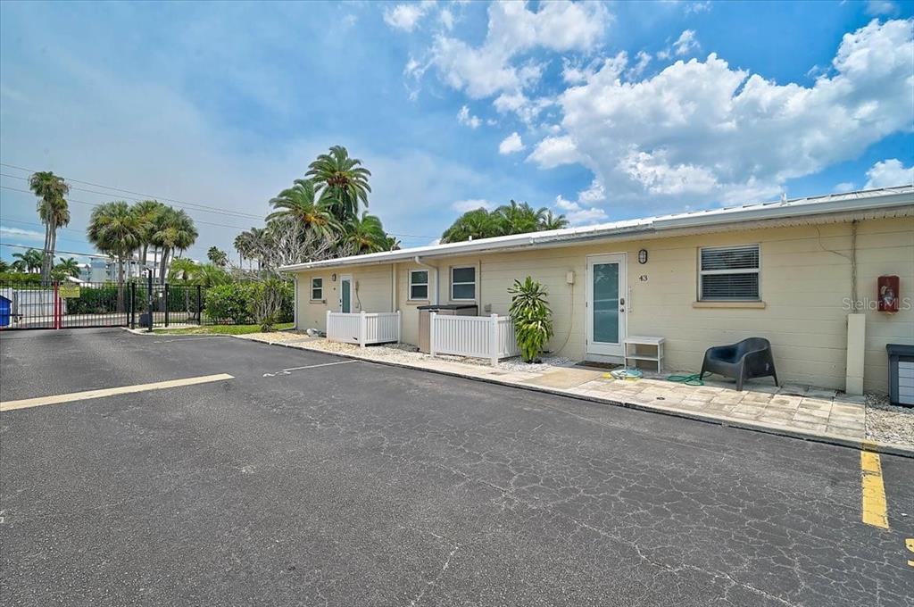 The exterior of a single-story, light-colored building with a parking lot in the foreground — 5830 MIDNIGHT PASS ROAD UNIT 43, SARASOTA, FL
