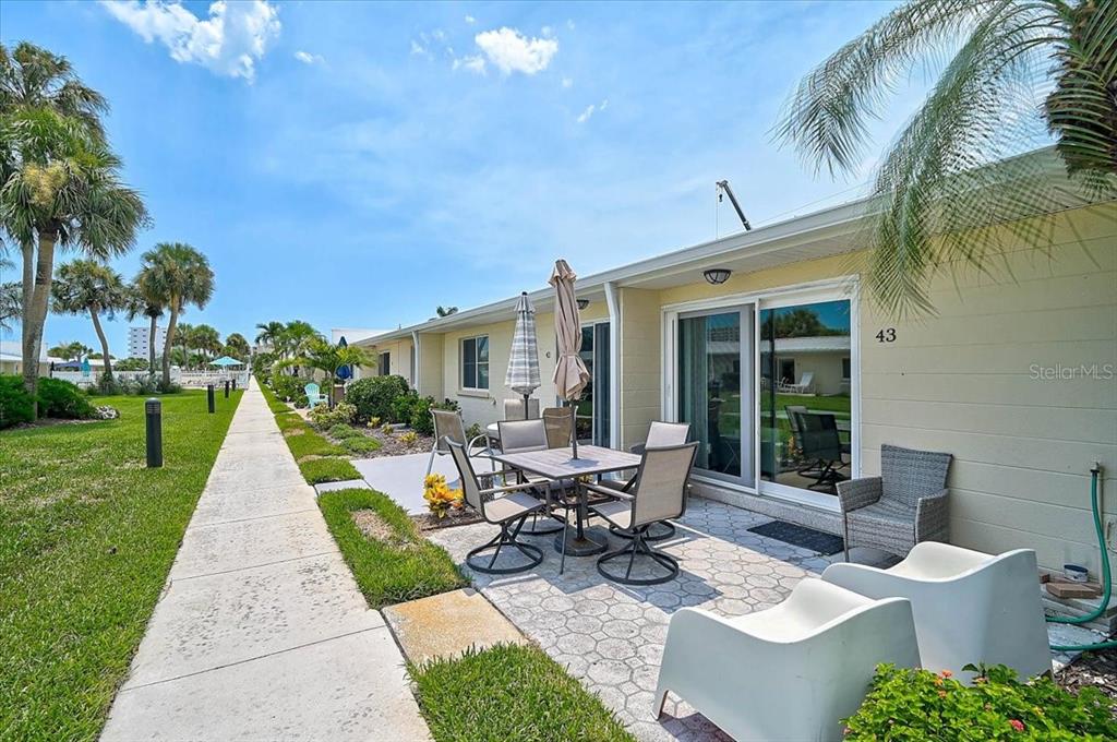 A patio with a dining set and chairs sits outside a unit numbered 43 — 5830 MIDNIGHT PASS ROAD UNIT 43, SARASOTA, FL