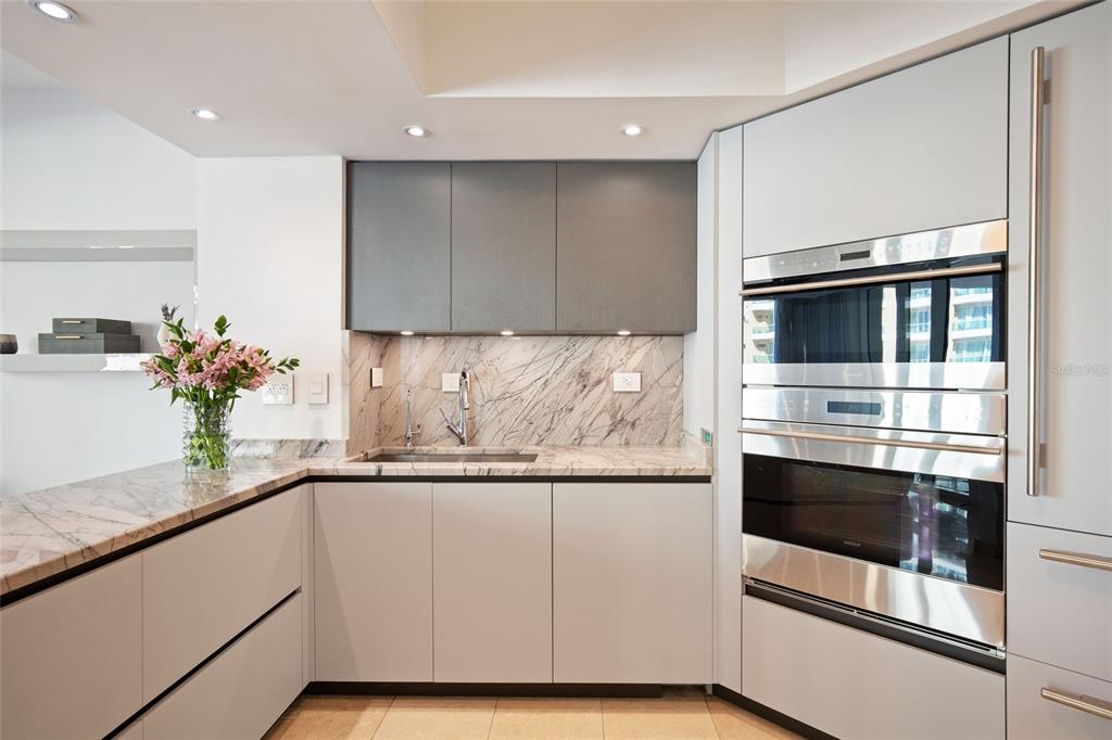 A kitchen features light gray cabinetry, marble countertops, a stainless steel oven, and a sink — 5 AVE MUNOZ RIVERA UNIT 404, SAN JUAN, PR