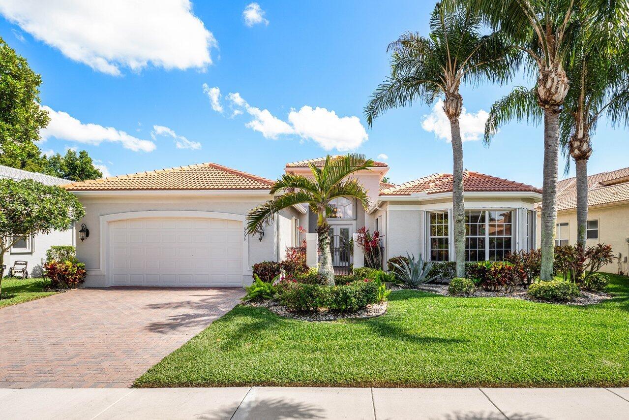 A single-story house with a two-car garage, tile roof, and palm trees in the front yard — 6558 Sand City Way, Delray Beach FL 33446, DELRAY BEACH, FL