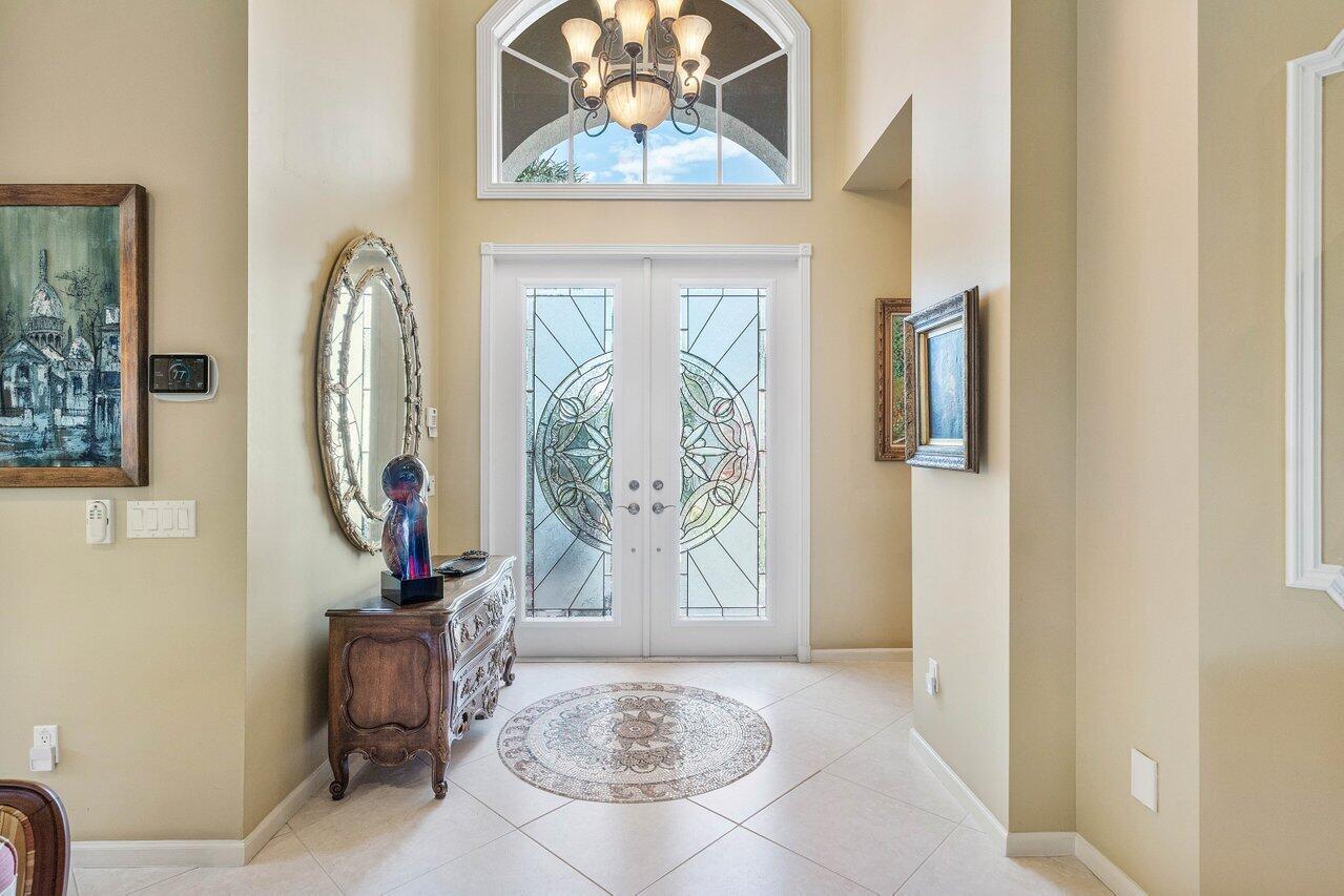 A bright entryway features a double glass door, a chandelier, and a circular area rug — 6558 Sand City Way, Delray Beach FL 33446, DELRAY BEACH, FL