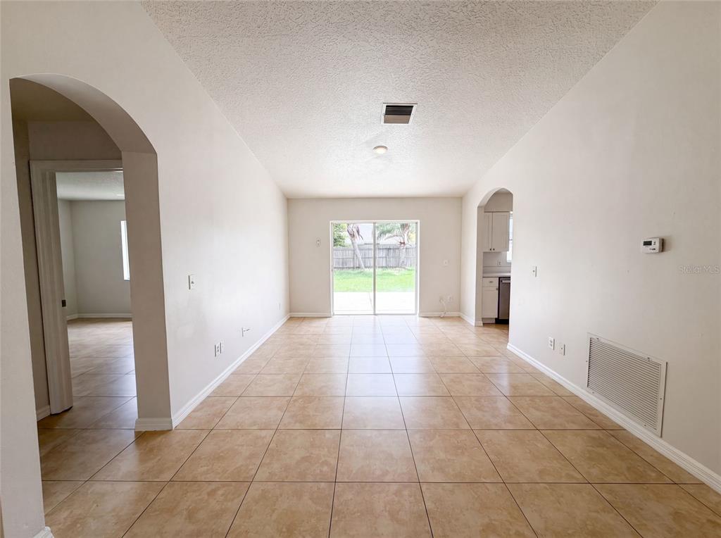An open living area features beige tile flooring, white walls, and a sliding glass door — 13236 PIKE LAKE DRIVE, RIVERVIEW, FL