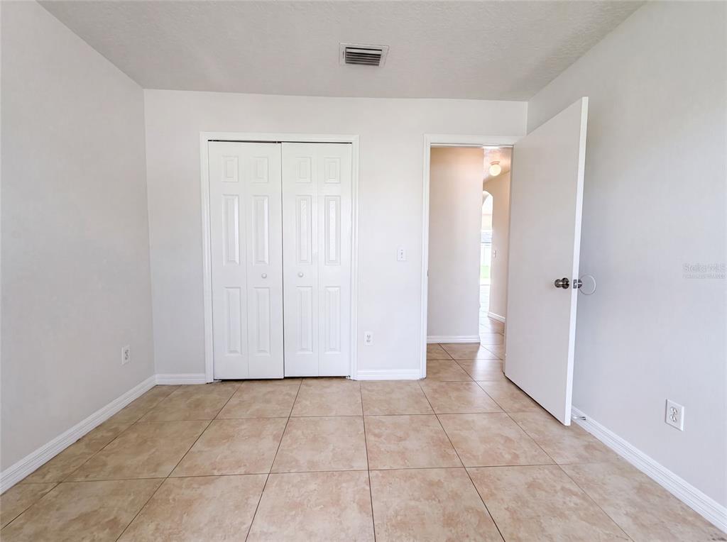 A room with light-colored walls, tiled flooring, a white closet, and an open doorway — 13236 PIKE LAKE DRIVE, RIVERVIEW, FL