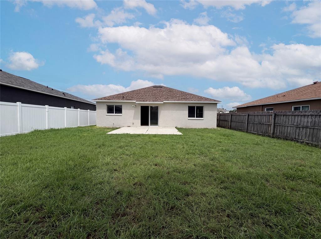 The backyard features a concrete patio, a sliding glass door, and white vinyl fencing — 13236 PIKE LAKE DRIVE, RIVERVIEW, FL