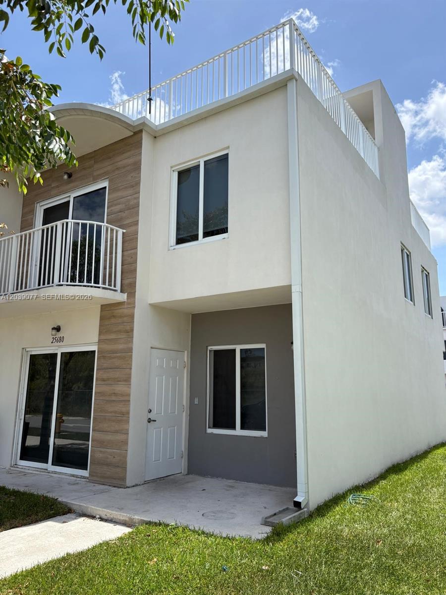 A two-story townhouse features a white stucco exterior, a balcony, and a rooftop terrace — 25680 SW 143rd Path, Homestead FL 33032, HOMESTEAD, FL