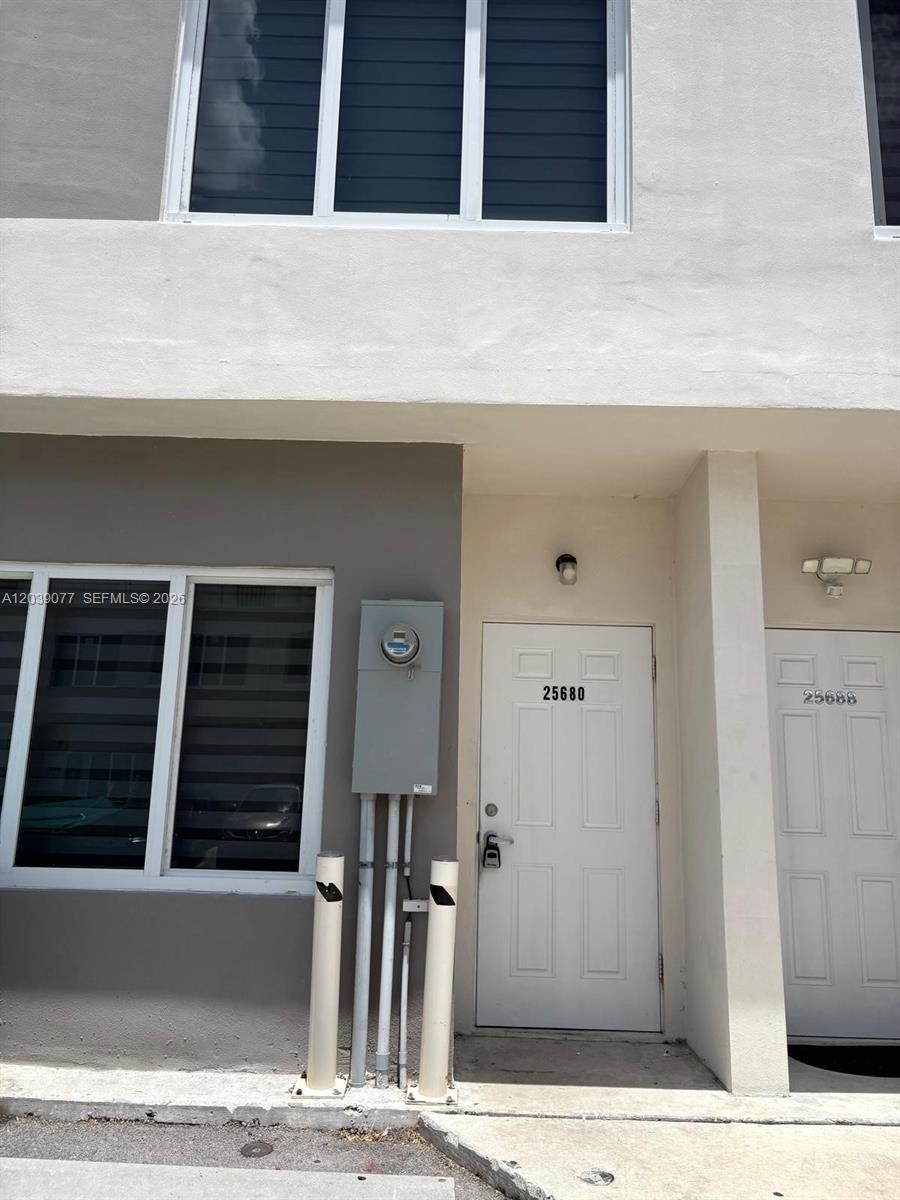 The exterior of a two-story townhouse features a white door labeled 25680 and bollards — 25680 SW 143rd Path, Homestead FL 33032, HOMESTEAD, FL