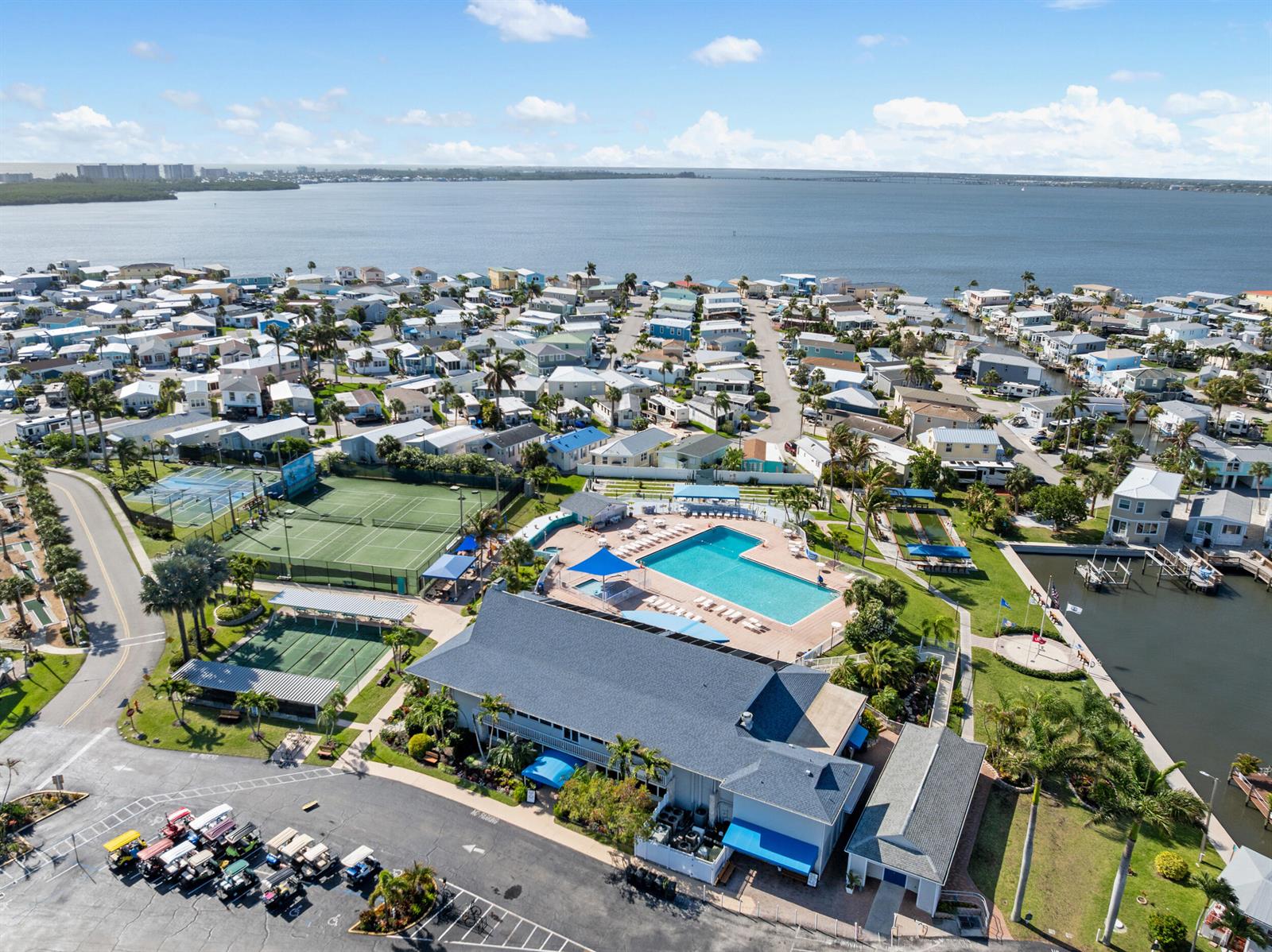An aerial view shows a community clubhouse with a pool, tennis courts, and nearby homes — 340 Nettles Boulevard, Jensen Beach FL 34957, JENSEN BEACH, FL