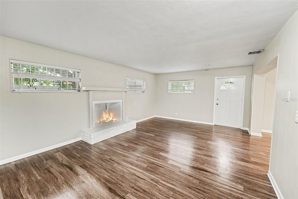 A living room with wood-look flooring, a white brick fireplace, and a white front door — 2098 62ND TERRACE S, ST PETERSBURG, FL