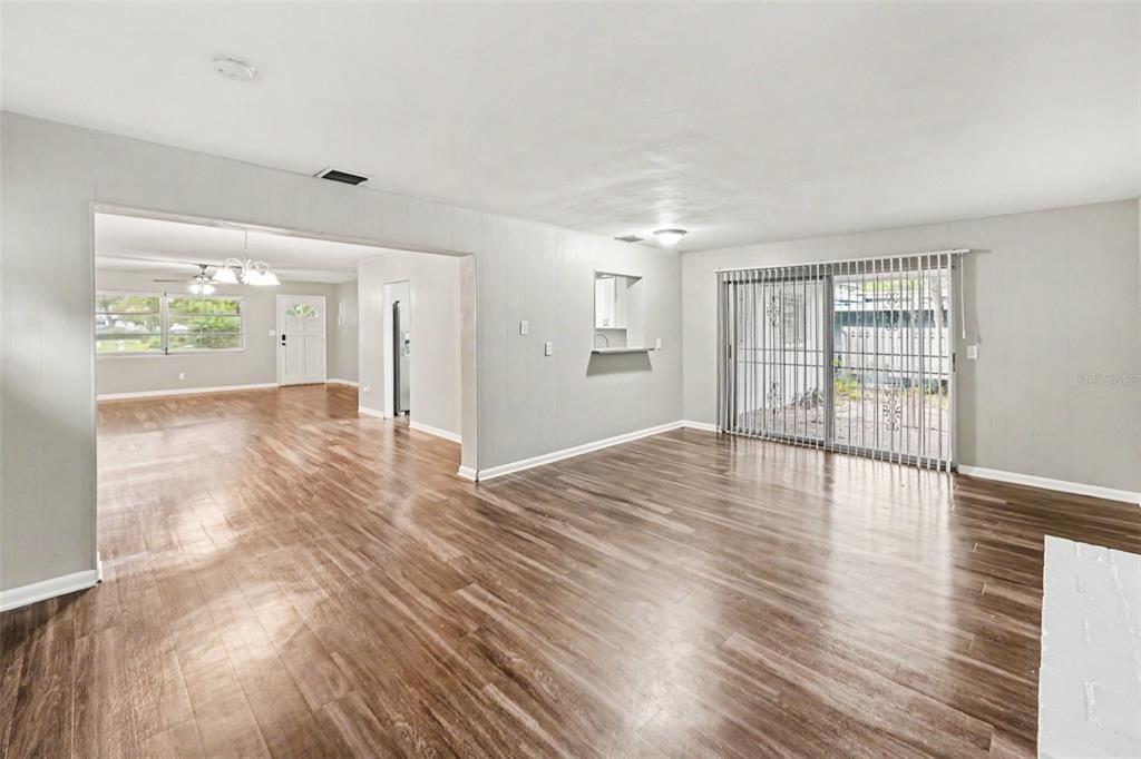 An open-concept living area features light gray walls, wood-look flooring, and sliding glass patio doors — 2098 62ND TERRACE S, ST PETERSBURG, FL