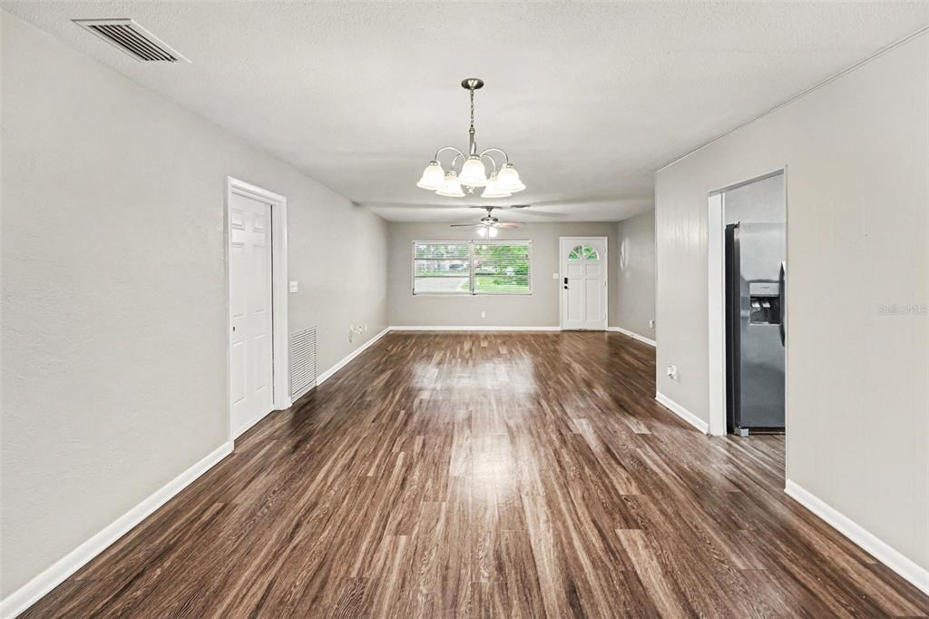 A living room with wood-look flooring, a white ceiling fan, and a central chandelier — 2098 62ND TERRACE S, ST PETERSBURG, FL