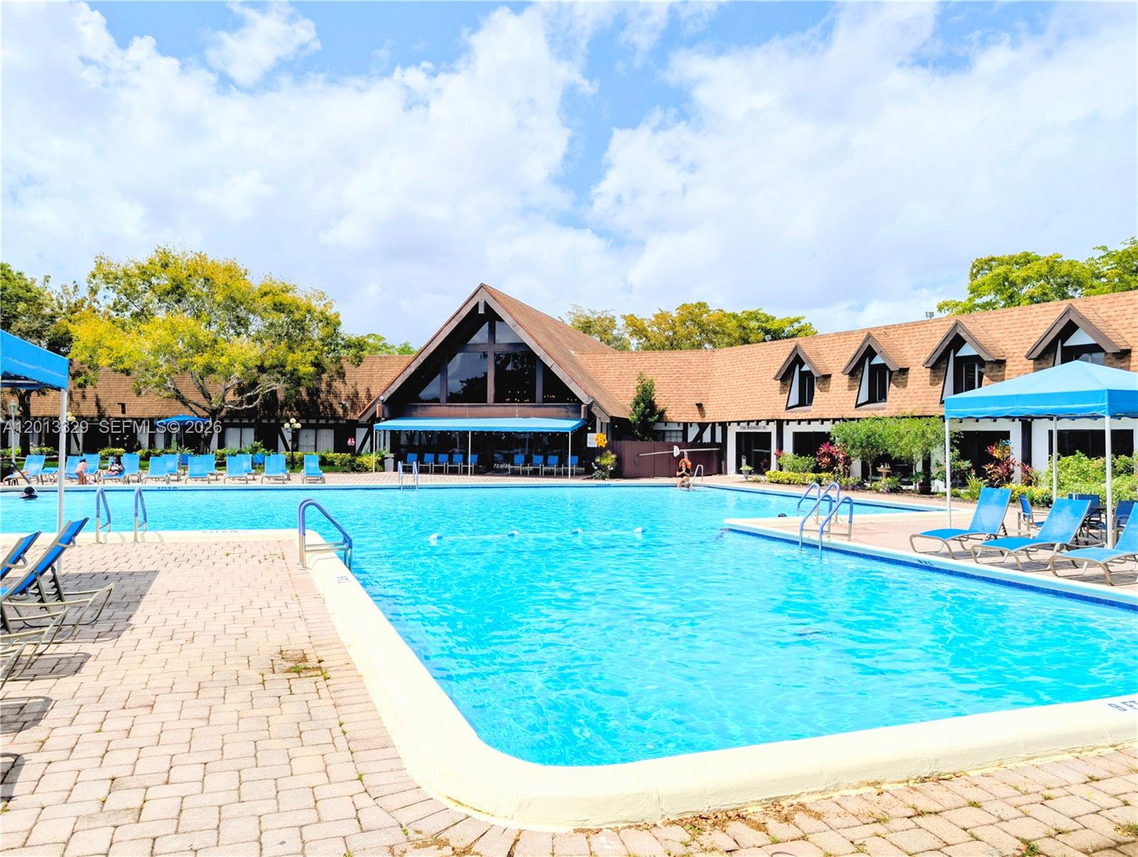 A large swimming pool sits in front of a building with a brown roof — 3740 Inverrary Dr # 2B, Lauderhill FL 33319, LAUDERHILL, FL