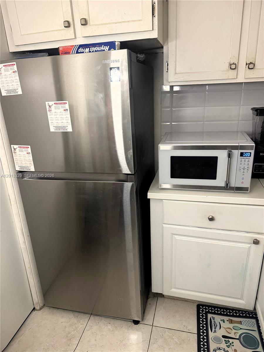 A stainless steel refrigerator stands next to a white microwave on a kitchen counter — 3740 Inverrary Dr # 2B, Lauderhill FL 33319, LAUDERHILL, FL