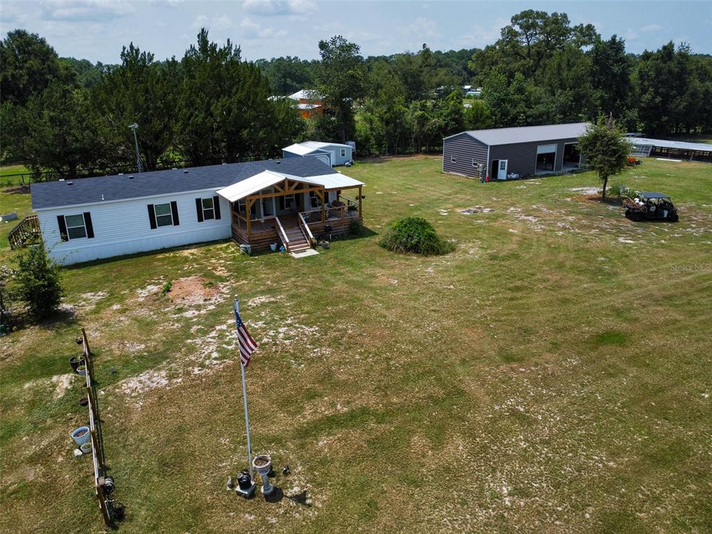 An aerial view shows a manufactured home with a porch, a detached garage, and yard — 330 SW CHALET TERRACE, FORT WHITE, FL