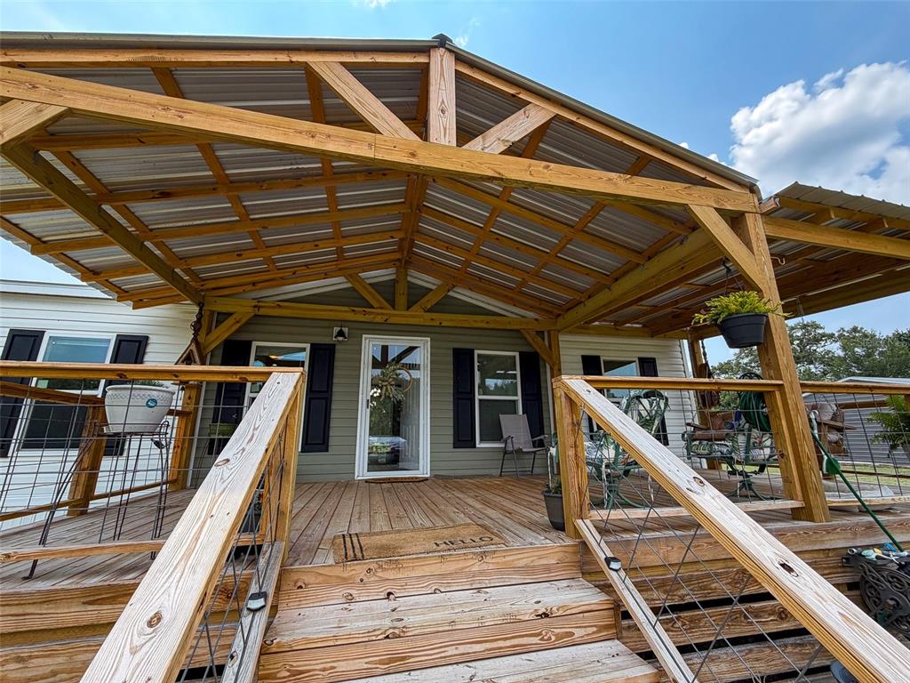 A wooden deck with a metal-roofed porch cover leads to the front door of a house — 330 SW CHALET TERRACE, FORT WHITE, FL