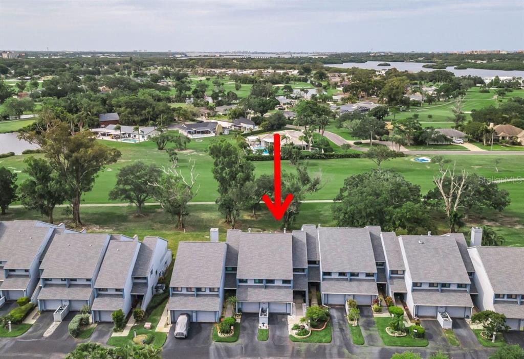 An aerial view shows a row of townhouses overlooking a golf course with a red arrow — 9150 PARK BOULEVARD UNIT 6, SEMINOLE, FL