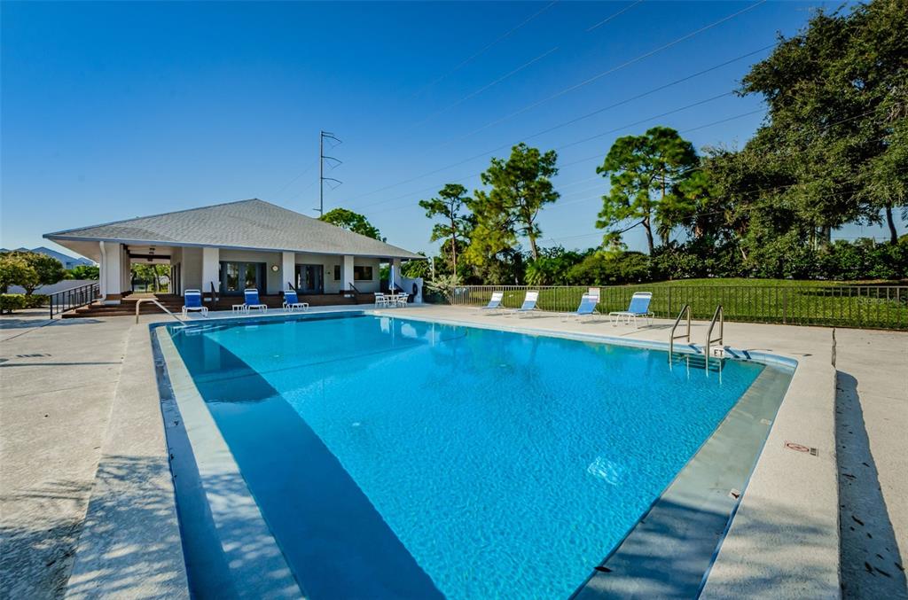 A rectangular swimming pool sits in front of a clubhouse with a covered patio — 9150 PARK BOULEVARD UNIT 6, SEMINOLE, FL