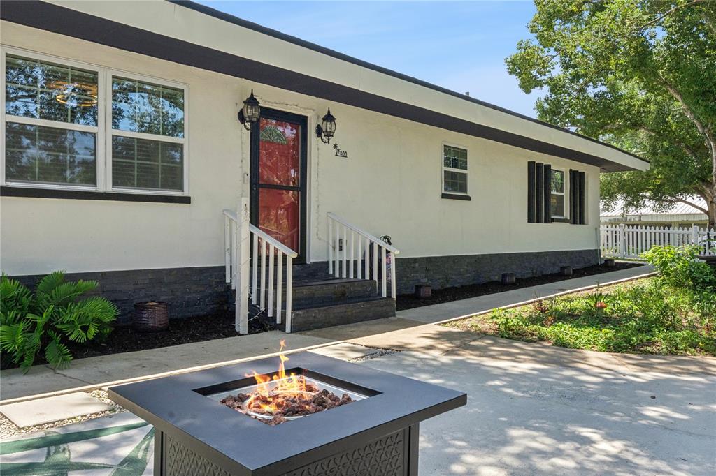 A fire pit sits on a concrete patio in front of a white house — 400 S RIDGEWOOD AVENUE, ORMOND BEACH, FL