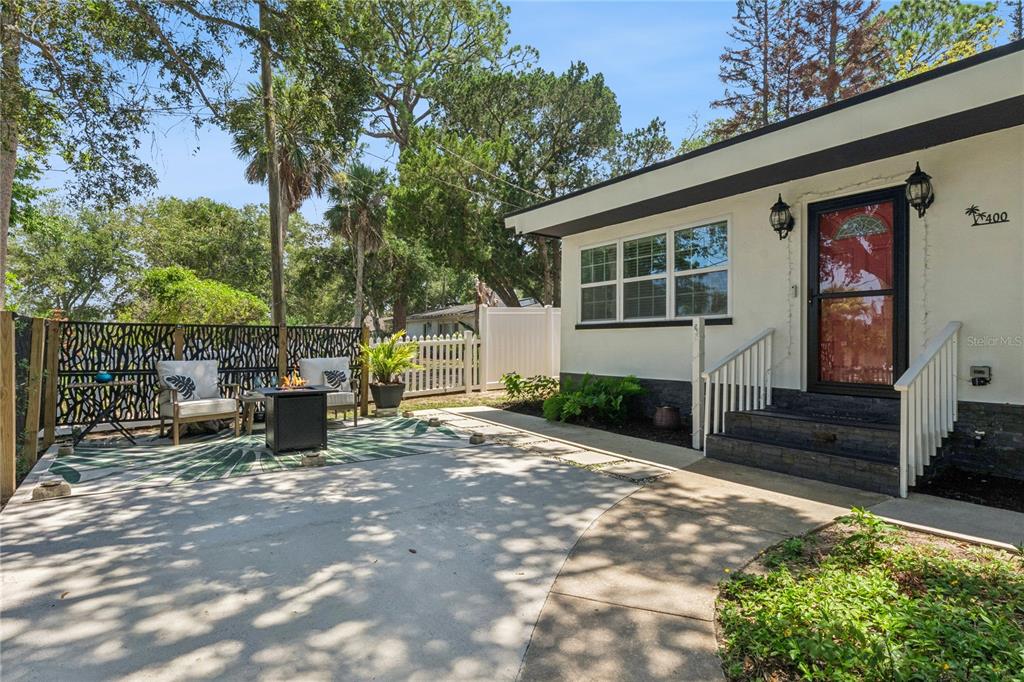 A concrete patio with a fire pit and seating sits beside a white house exterior — 400 S RIDGEWOOD AVENUE, ORMOND BEACH, FL