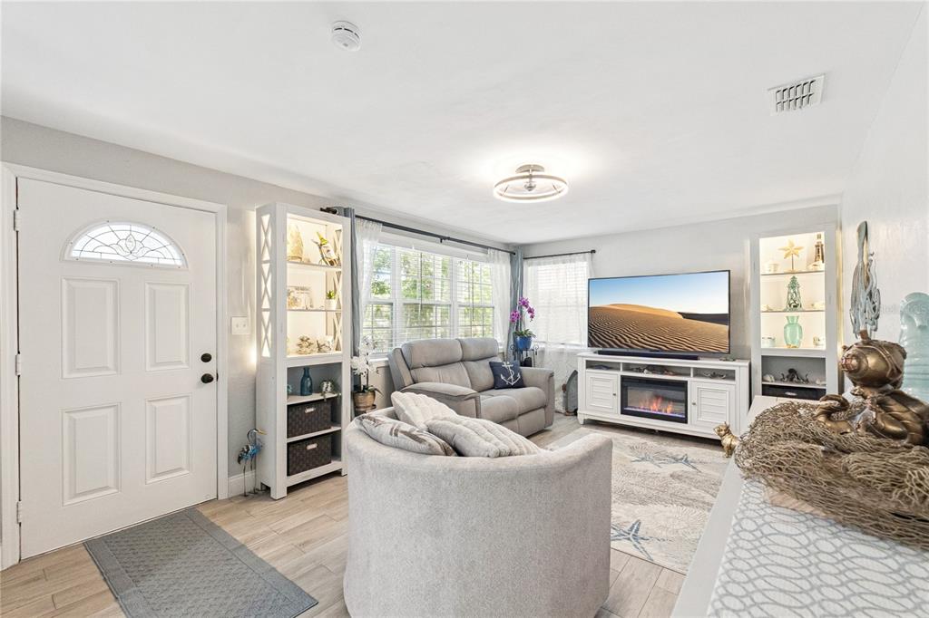 A living room features a white fireplace console, gray seating, and built-in shelving units — 400 S RIDGEWOOD AVENUE, ORMOND BEACH, FL