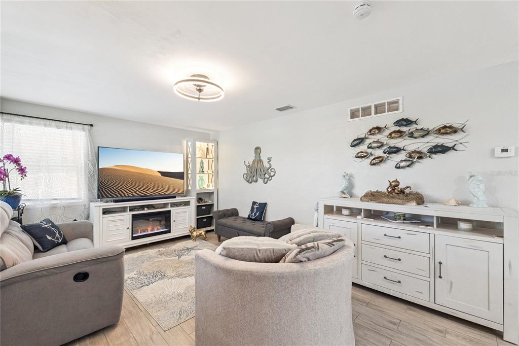 A living room features a television, fireplace console, coastal decor, and light-colored wood flooring — 400 S RIDGEWOOD AVENUE, ORMOND BEACH, FL