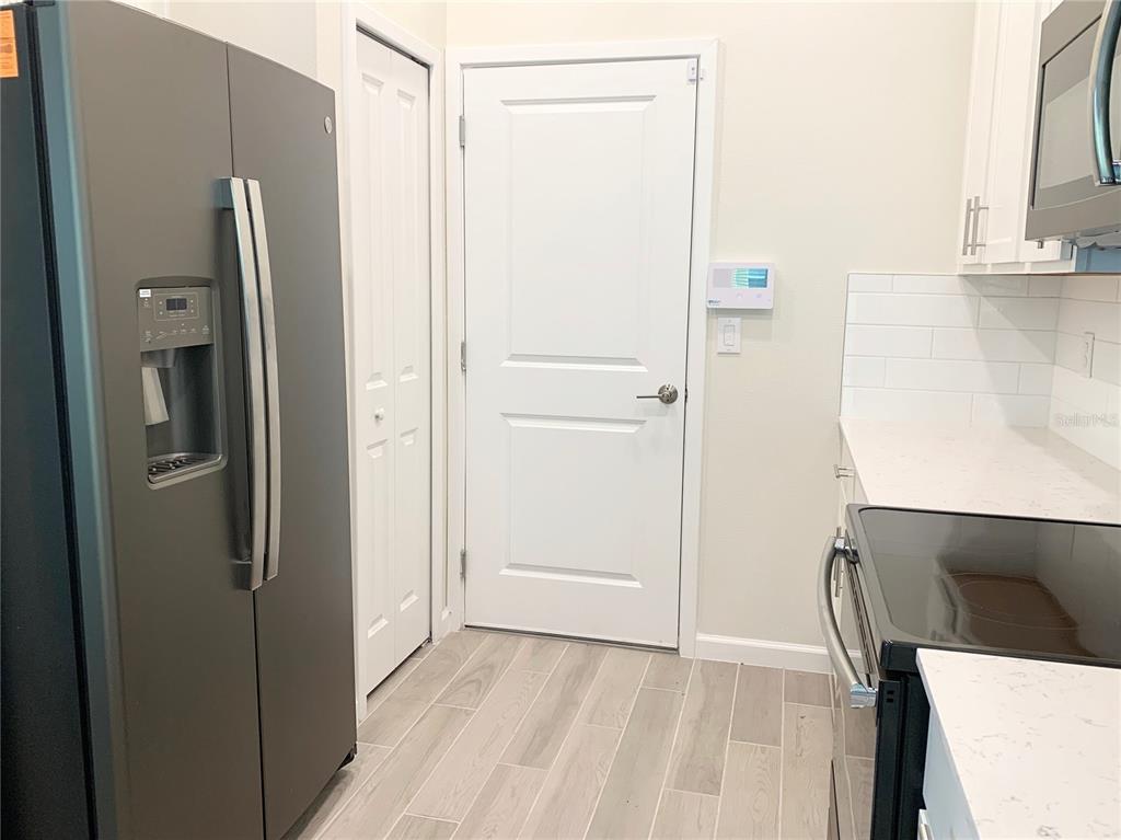 A kitchen features a dark refrigerator, white cabinets, light countertops, and a white interior door — 9963 RED EAGLE DRIVE, ORLANDO, FL