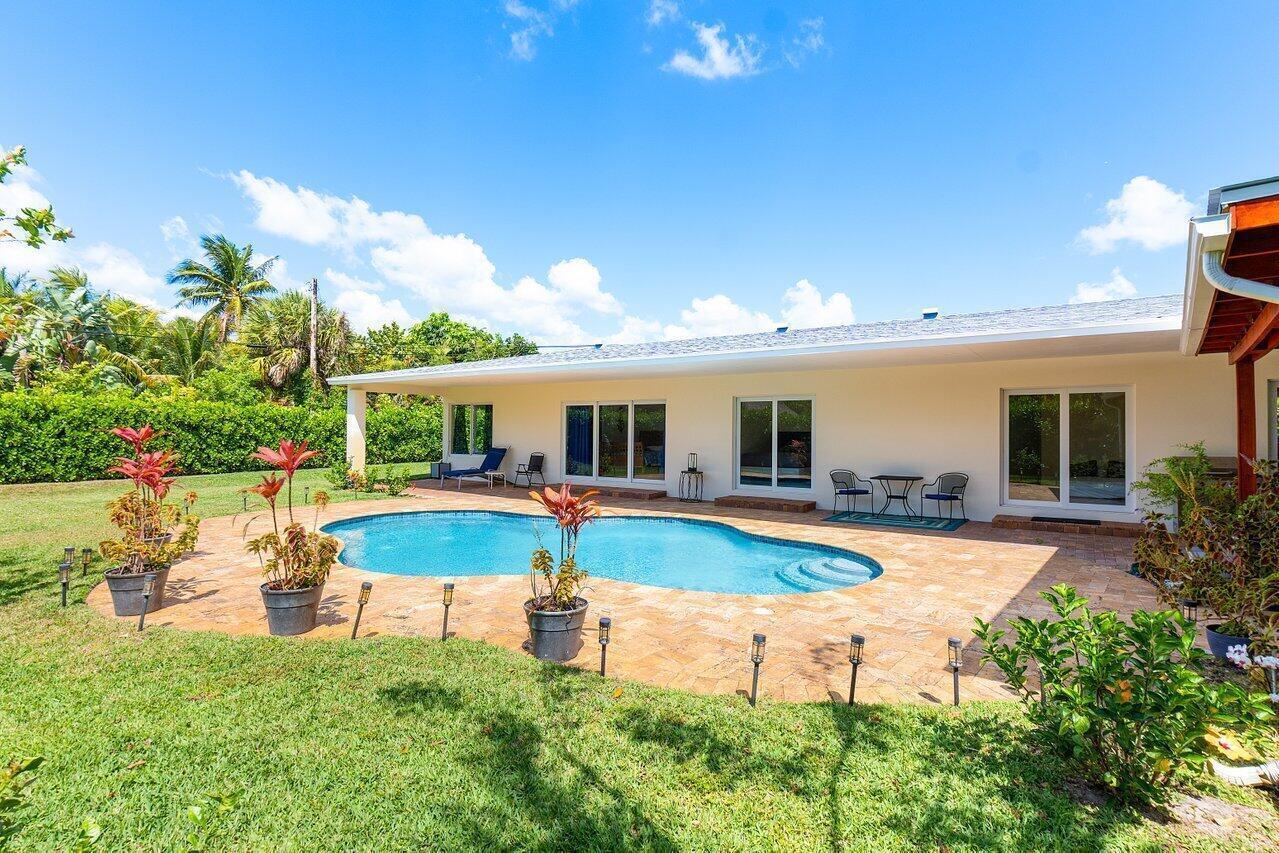A backyard features a swimming pool, a paved patio, and a single-story house exterior — 1650 NE 3rd Avenue, Delray Beach FL 33444, DELRAY BEACH, FL