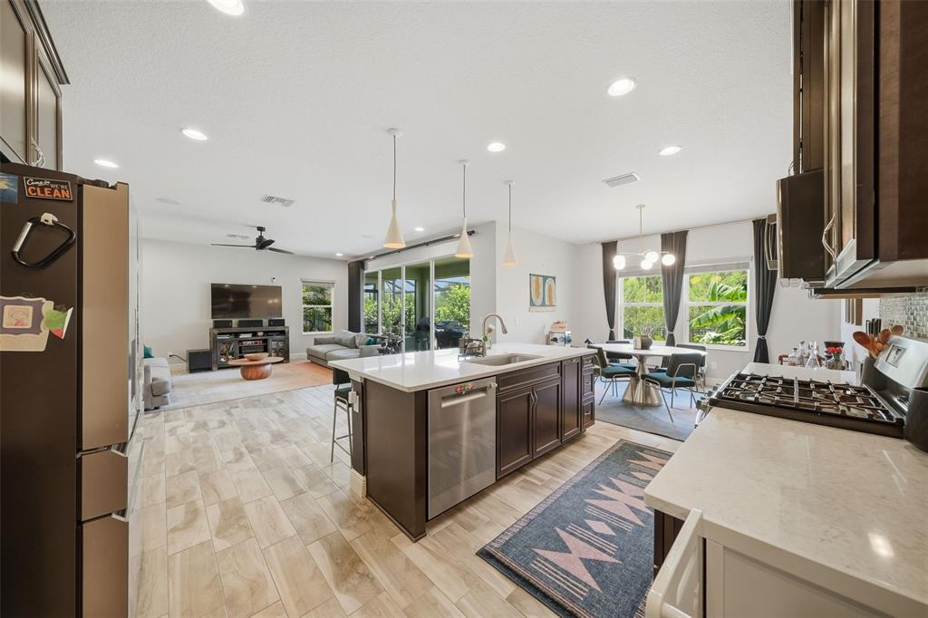 A modern open-concept kitchen features dark cabinetry, white countertops, and a large central island — 4801 BALLANTRAE BOULEVARD, LAND O LAKES, FL