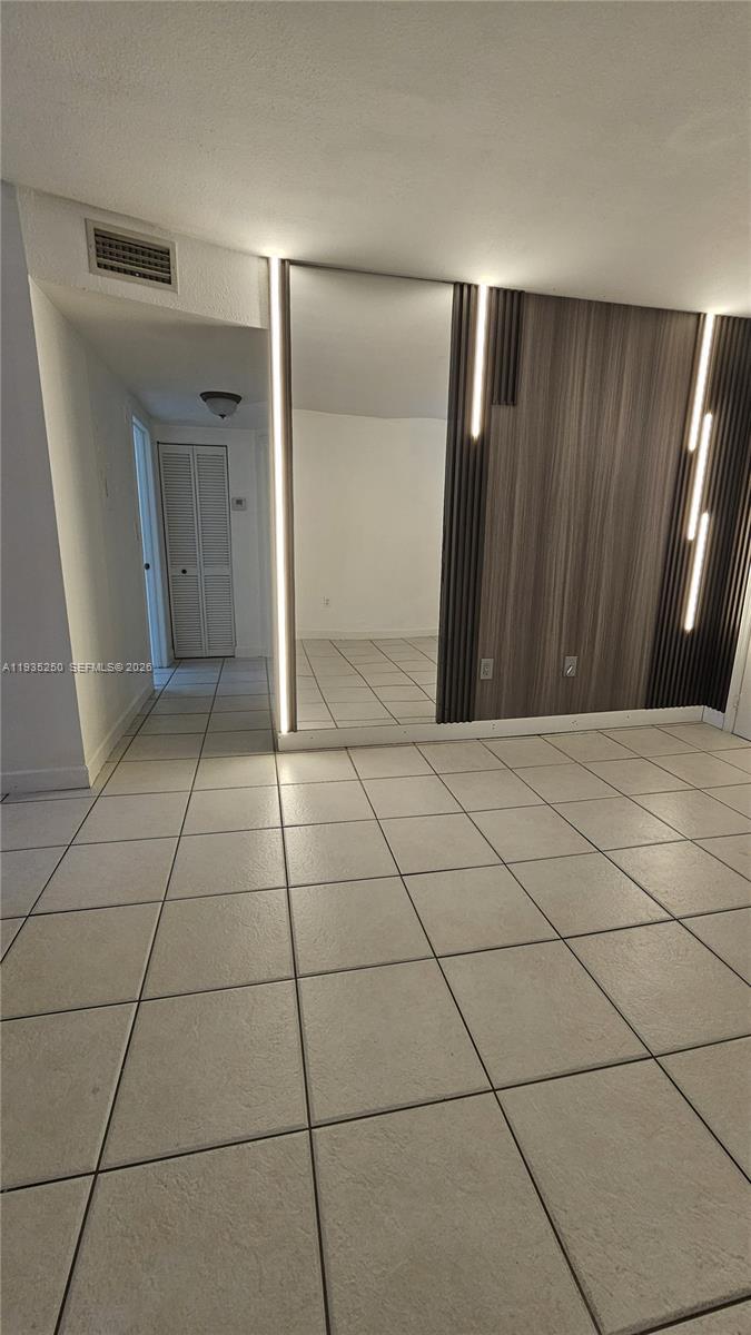 A room features light-colored floor tiles, a mirrored wall, and a wood-paneled accent wall — 5460 W 21st CT # 310, Hialeah FL 33016, HIALEAH, FL