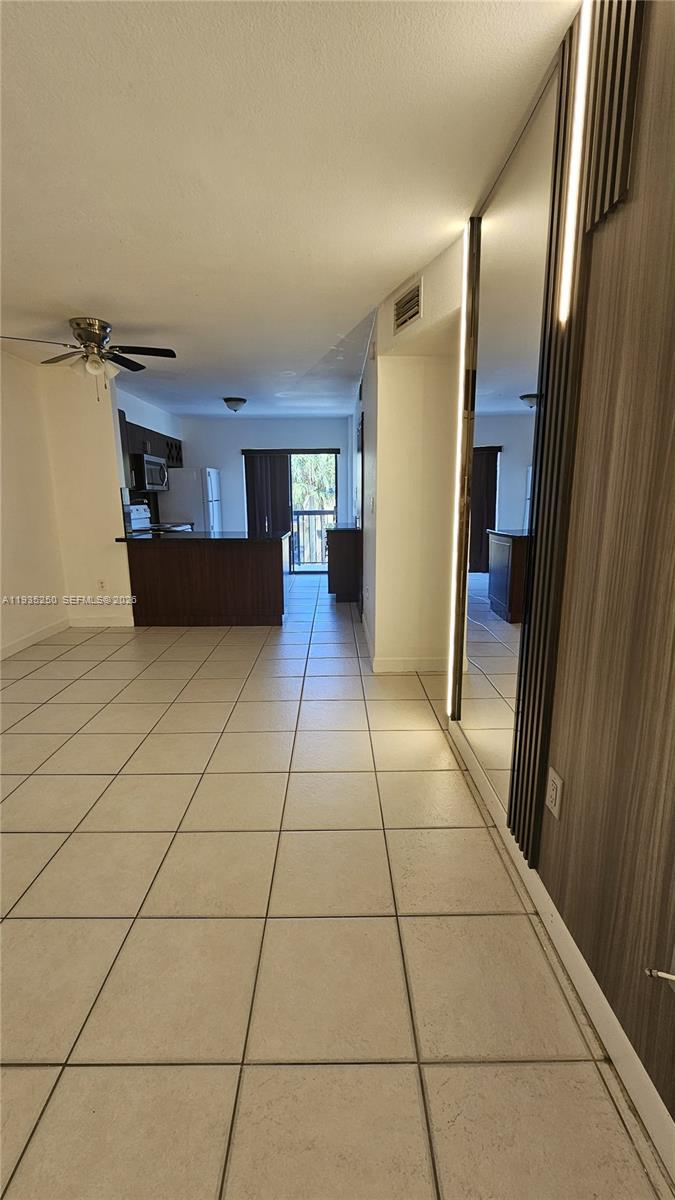 A tiled hallway leads to an open kitchen with a breakfast bar and balcony access — 5460 W 21st CT # 310, Hialeah FL 33016, HIALEAH, FL