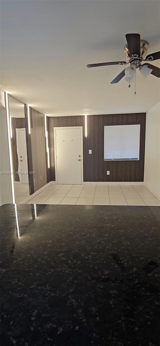 A room with a dark slatted accent wall, white tile floors, and a ceiling fan — 5460 W 21st CT # 310, Hialeah FL 33016, HIALEAH, FL