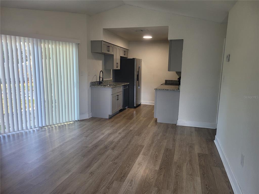 A kitchen with gray cabinets and wood-look flooring opens to a living area with blinds — 1236 DOVEHILL DRIVE UNIT 1248, APOPKA, FL