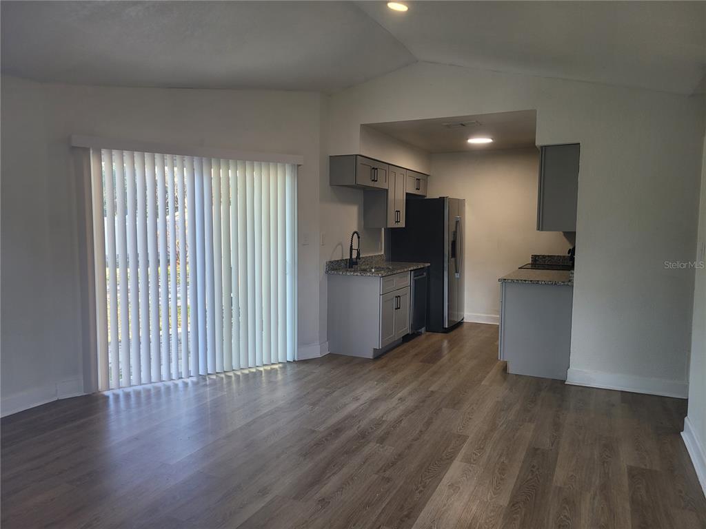 A kitchen with gray cabinets and stainless steel appliances opens into a living area — 1236 DOVEHILL DRIVE UNIT 1248, APOPKA, FL