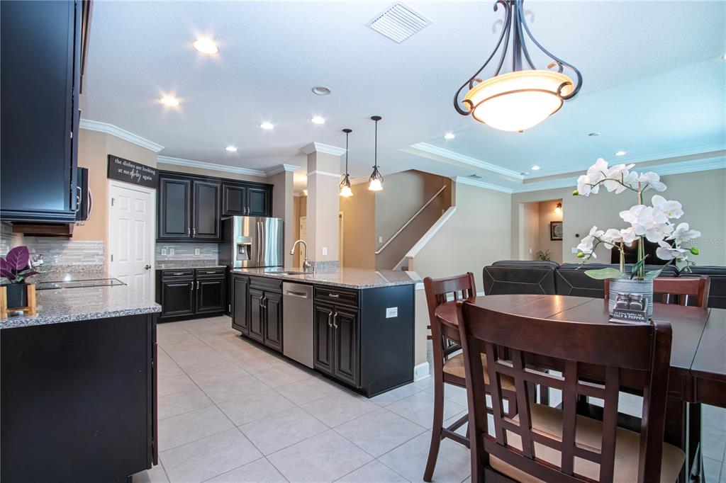 A kitchen with dark cabinets, granite countertops, and an island opens to a dining area — 5001 65TH TERRACE E, ELLENTON, FL