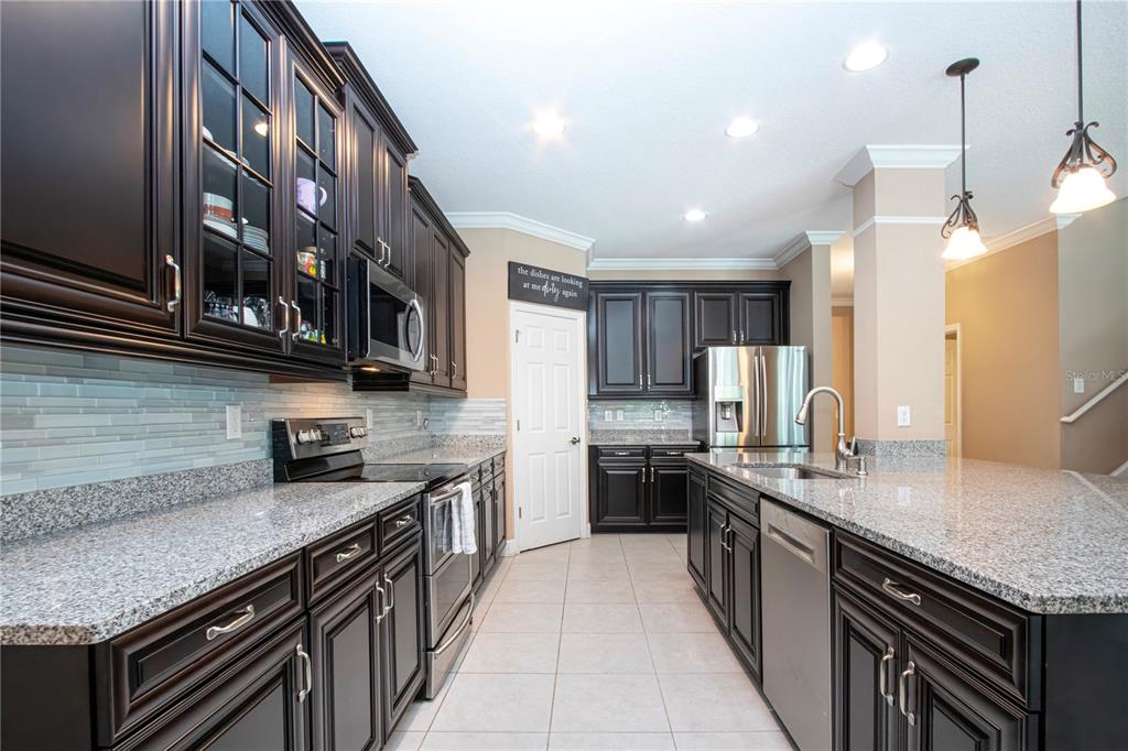 A kitchen features dark wood cabinets, granite countertops, stainless steel appliances, and a central island — 5001 65TH TERRACE E, ELLENTON, FL