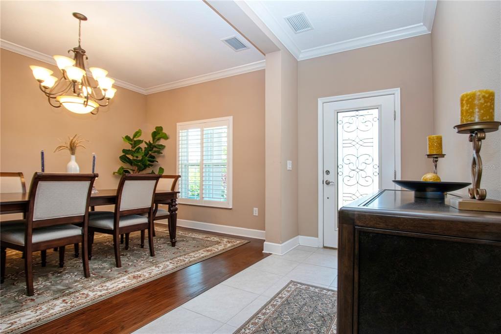 A dining room with hardwood floors and a chandelier sits next to a tiled entryway — 5001 65TH TERRACE E, ELLENTON, FL