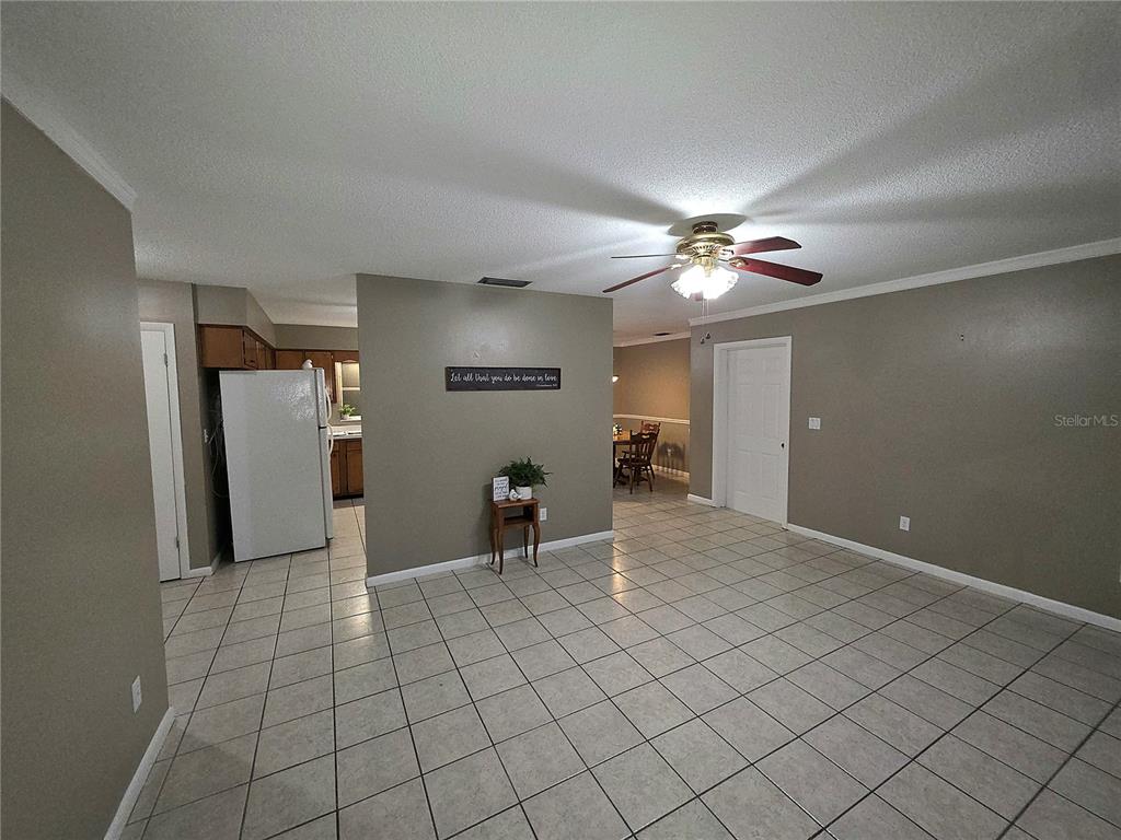 A tiled living area features a central wall, a ceiling fan, and an adjacent kitchen — 21654 SW RAINTREE STREET, DUNNELLON, FL