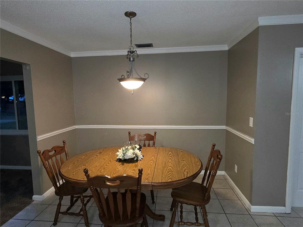 A dining room features a round wooden table, four chairs, and a hanging light fixture — 21654 SW RAINTREE STREET, DUNNELLON, FL